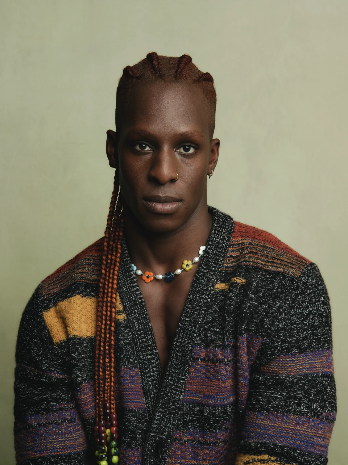 Studio portrait of a model in a multicoloured knitted cardigan and beaded necklace.