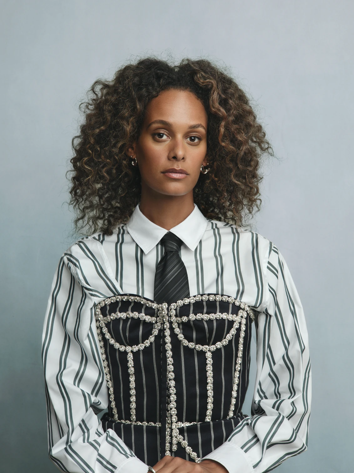 Studio portrait of a model in a striped shirt and crystal-trimmed corset.